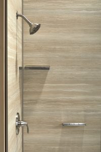 Close-up of a modern walk-in shower with floating shelves and chrome fixtures