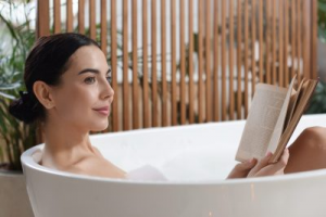 young woman relaxing in bath with a book