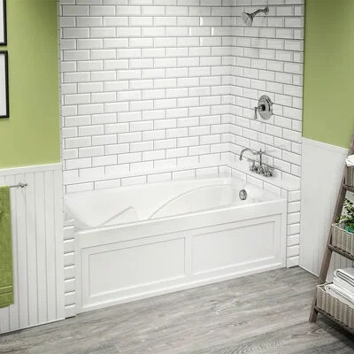 A large white tub with subway tile wall surrounds. 