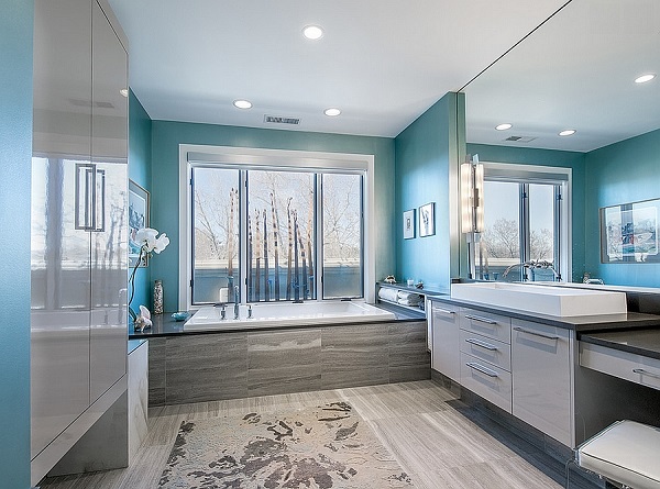 A large bathroom with teal walls, and large  vanity, and a standalone tub. 