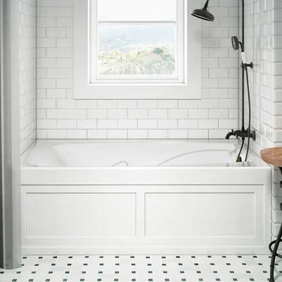 A large bathtub with a hand-held shower wand and subway tiling. 