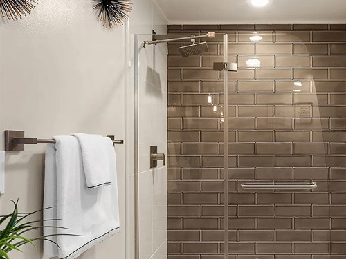 A walk-in shower with brown subway tile walls and a low-flow showerhead. 