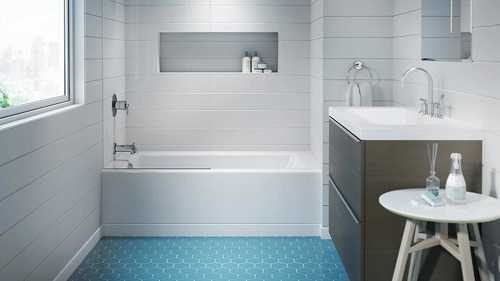 A bathroom tub with white subway tile walls and a blue tiled floor. 