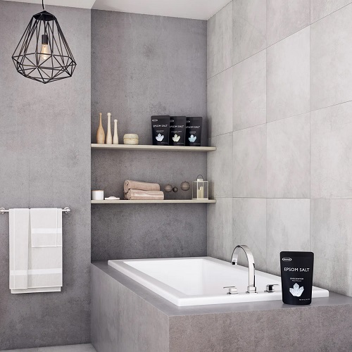 A sleek modern bathroom with gray marble walls and a drop-in tub. 