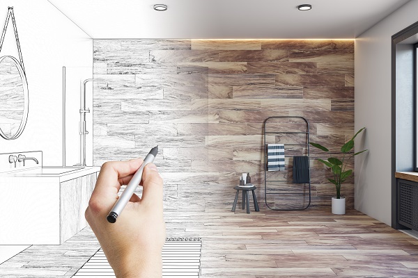 Human hand with pencil making design project of modern bathroom with stylish shower area, towel holder and green plant on a wood-effect tiles wall.