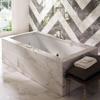 A larger deep-soaking jetted tub set in a marble-tiled frame.